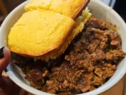 This image shows a bowl full of venison chili with cornbread on the side.